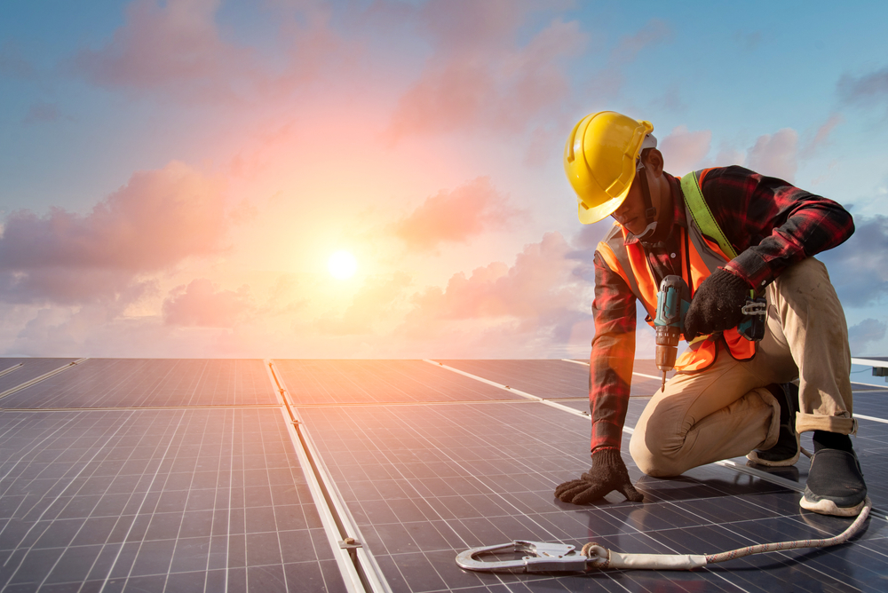 Electrician engineer works at the solar power station with a wrench in hand during a sunny day.