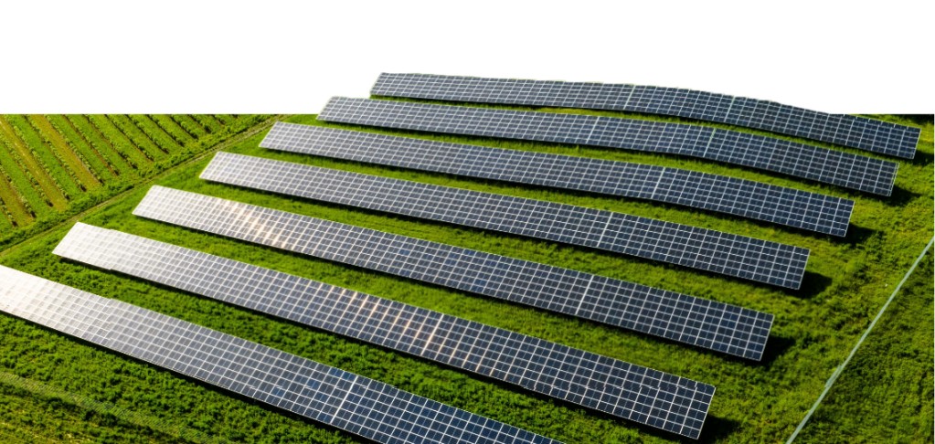 An aerial view of a solar farm with rows of photovoltaic panels installed amidst green fields, harnessing renewable energy from the sun through solar solutions.